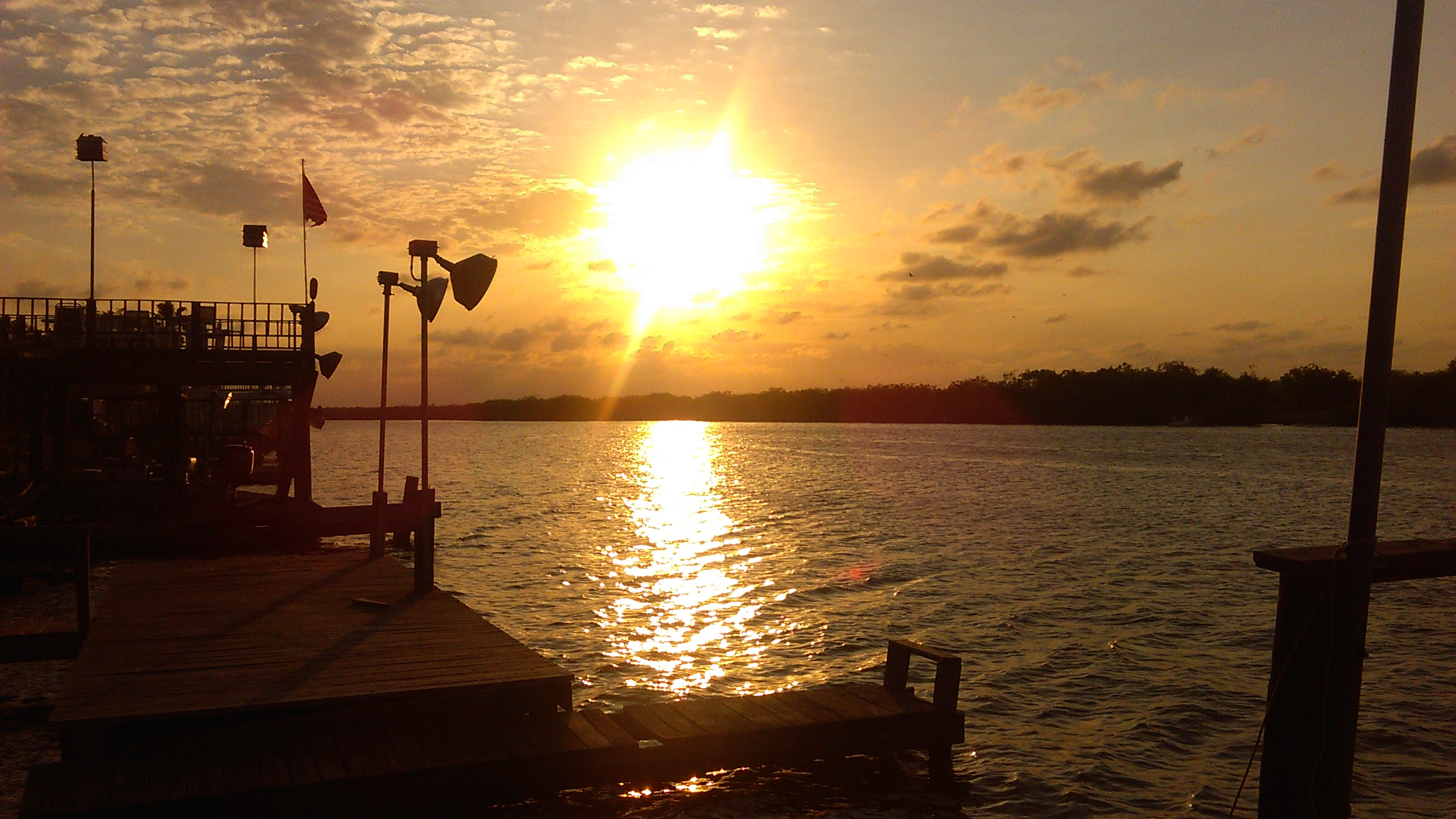 Sunset over calm lake with dock.
