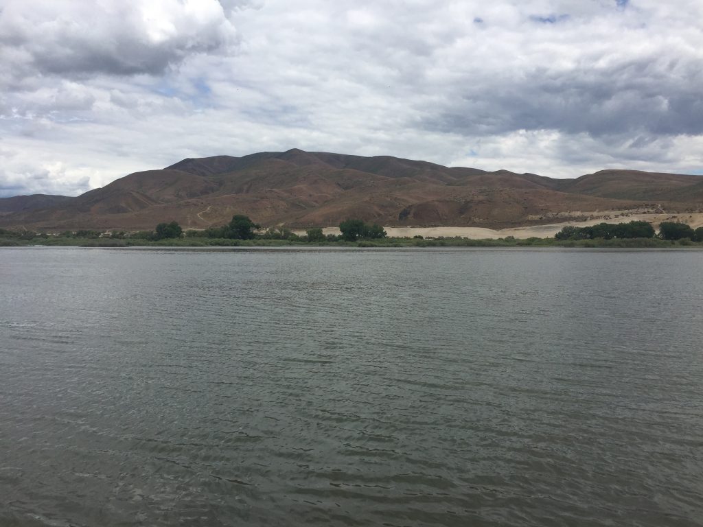 River with hills under a cloudy sky.