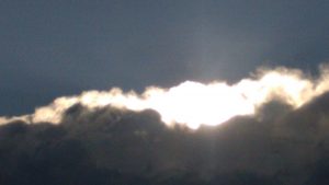Sunlight breaking through dark cloudy sky.