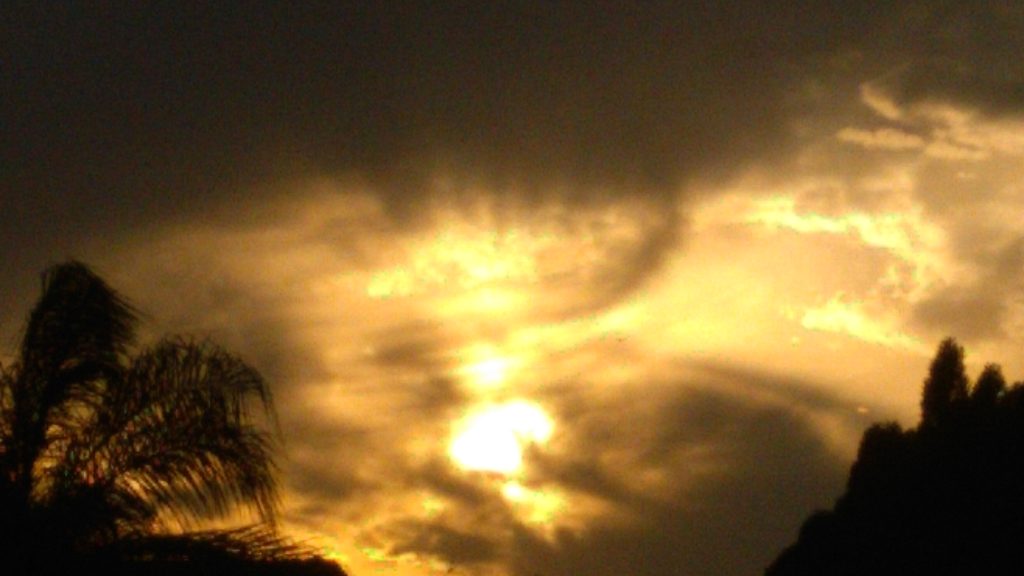 Dramatic sunset with silhouetted trees and clouds.