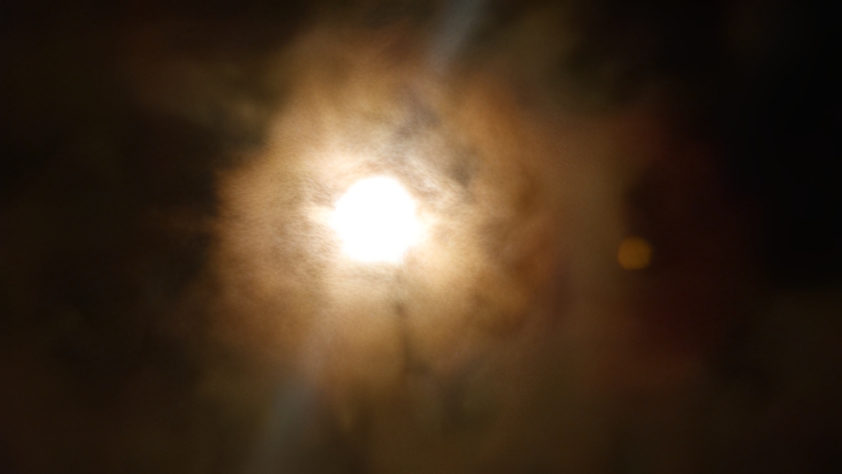 Bright sun obscured by swirling dark clouds.