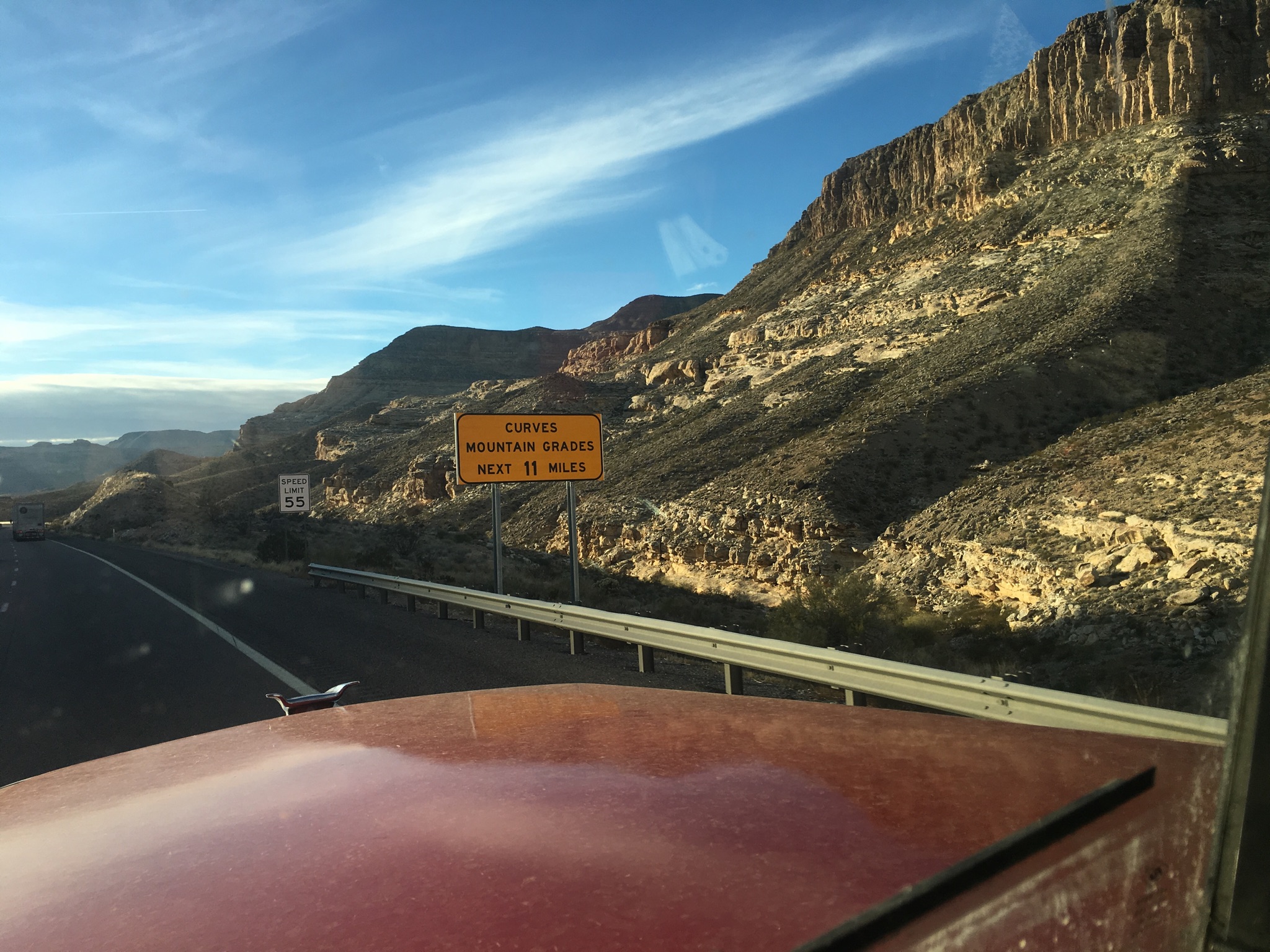 Mountain road with caution sign and cliffs.
