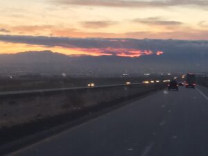 Highway at sunset with distant mountains.