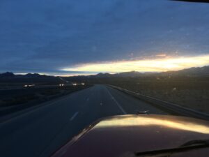 Desert highway at sunset with mountains.