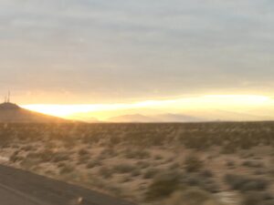 Desert sunrise with cloudy sky and mountains.