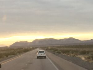 Cars on desert highway at sunset.
