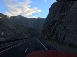 Mountain highway with rocky cliffs and sky.