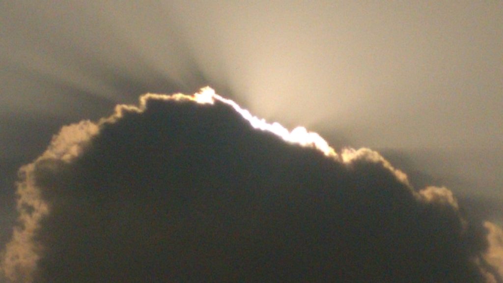 Sunlight shining behind a dark cloud.