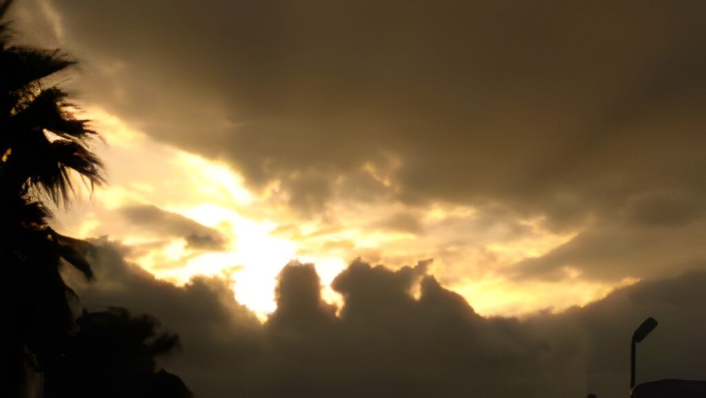 Sunset with dramatic clouds and silhouetted trees.