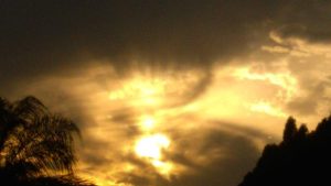 Dramatic sunset with silhouetted trees and clouds.