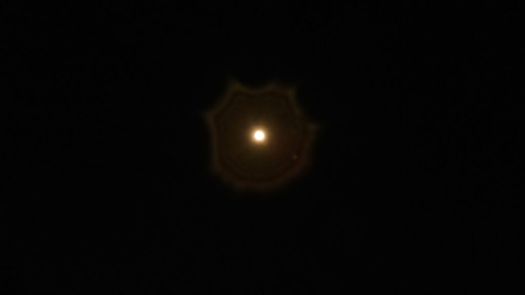 Bright light with circular halo in darkness.
