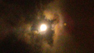 Bright moon surrounded by colorful, cloudy sky.