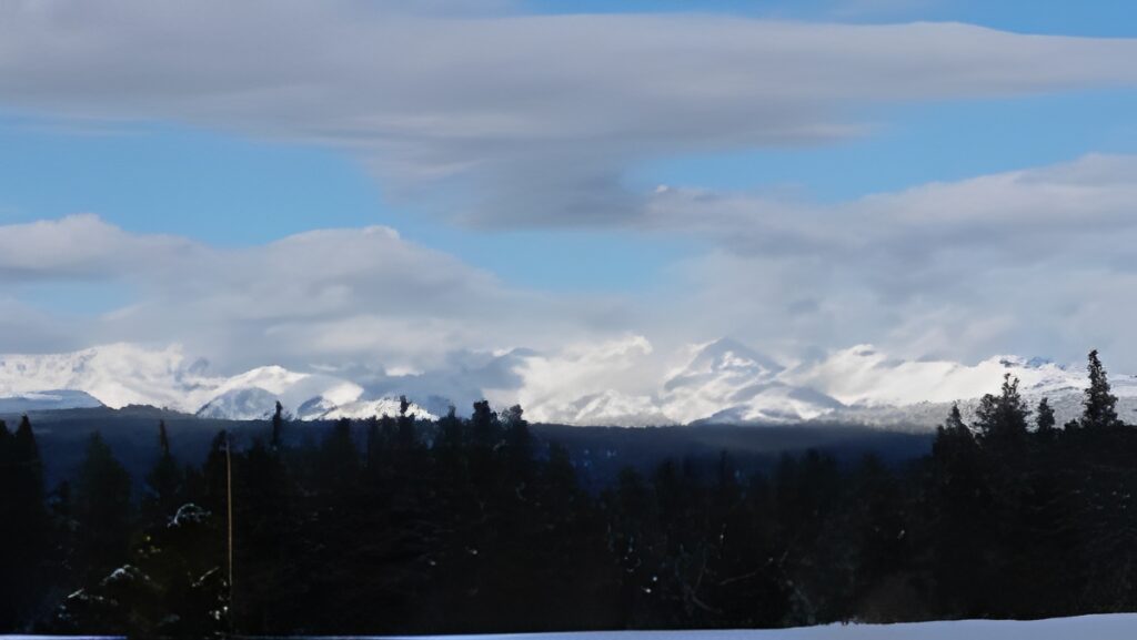 Snowy mountains under a cloudy blue sky.