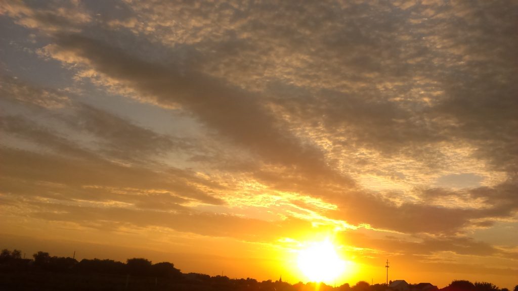 Golden sunset with scattered clouds in sky.