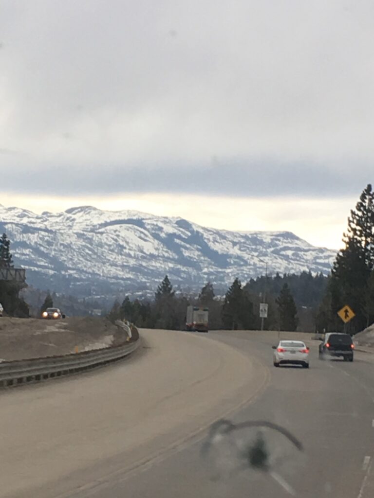 Mountain road with cars and snowy peaks.