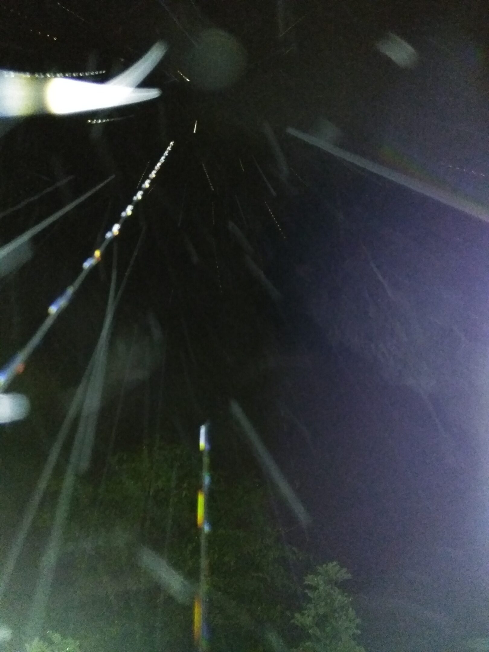 Nighttime rain with bright light streaks.