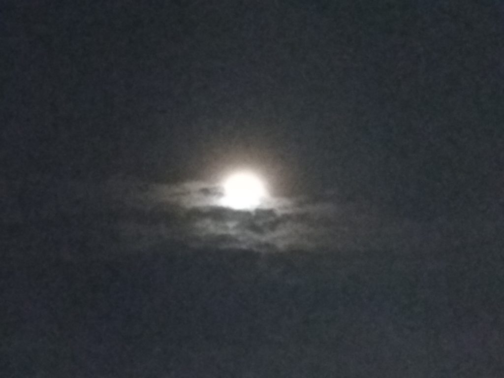 Bright moon shining through dark clouds.