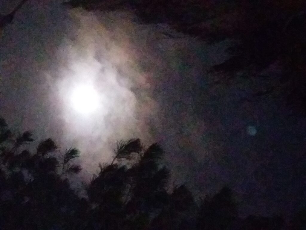 Moon shining through cloudy night sky.