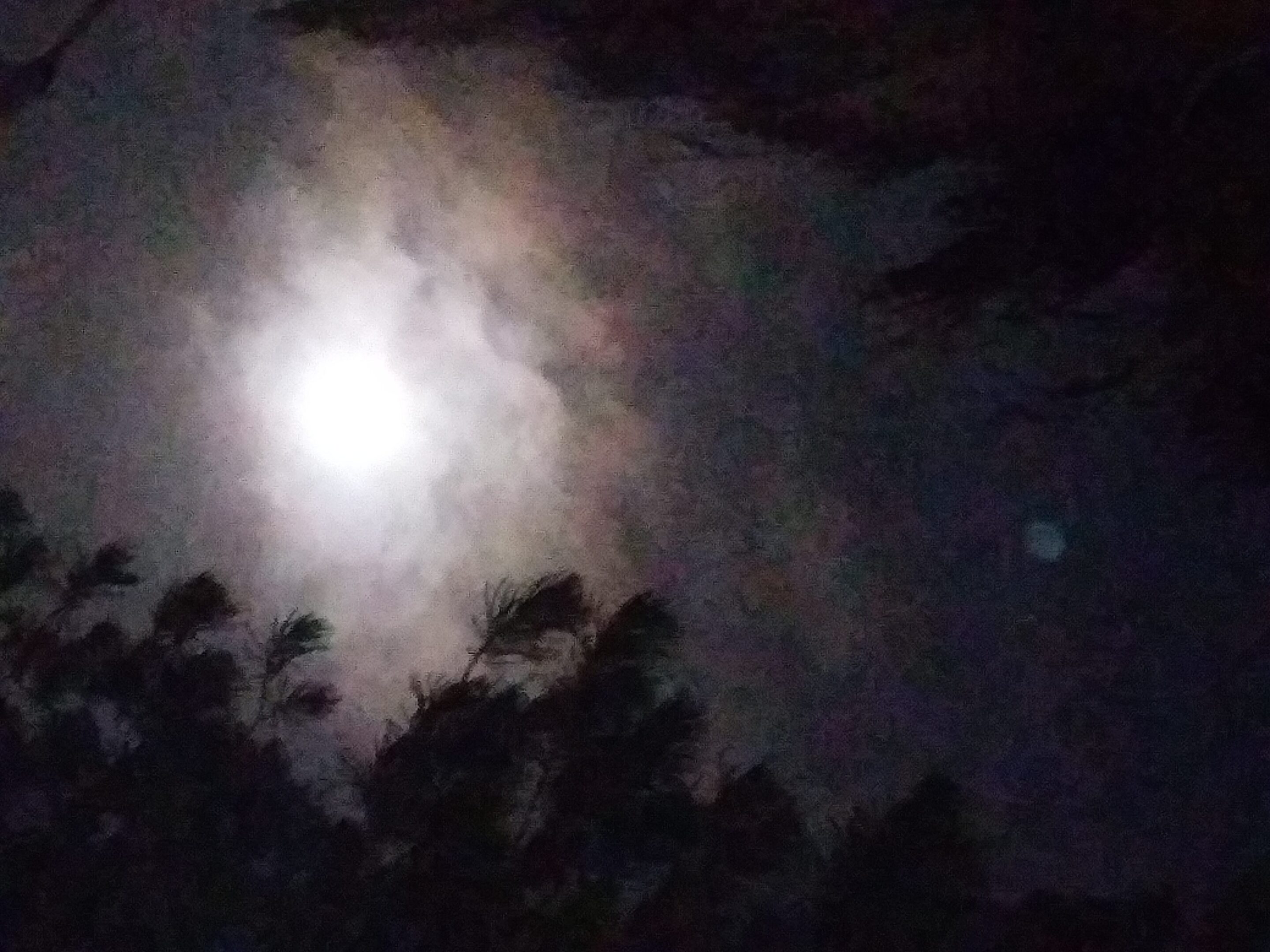 Moon shining through cloudy night sky.