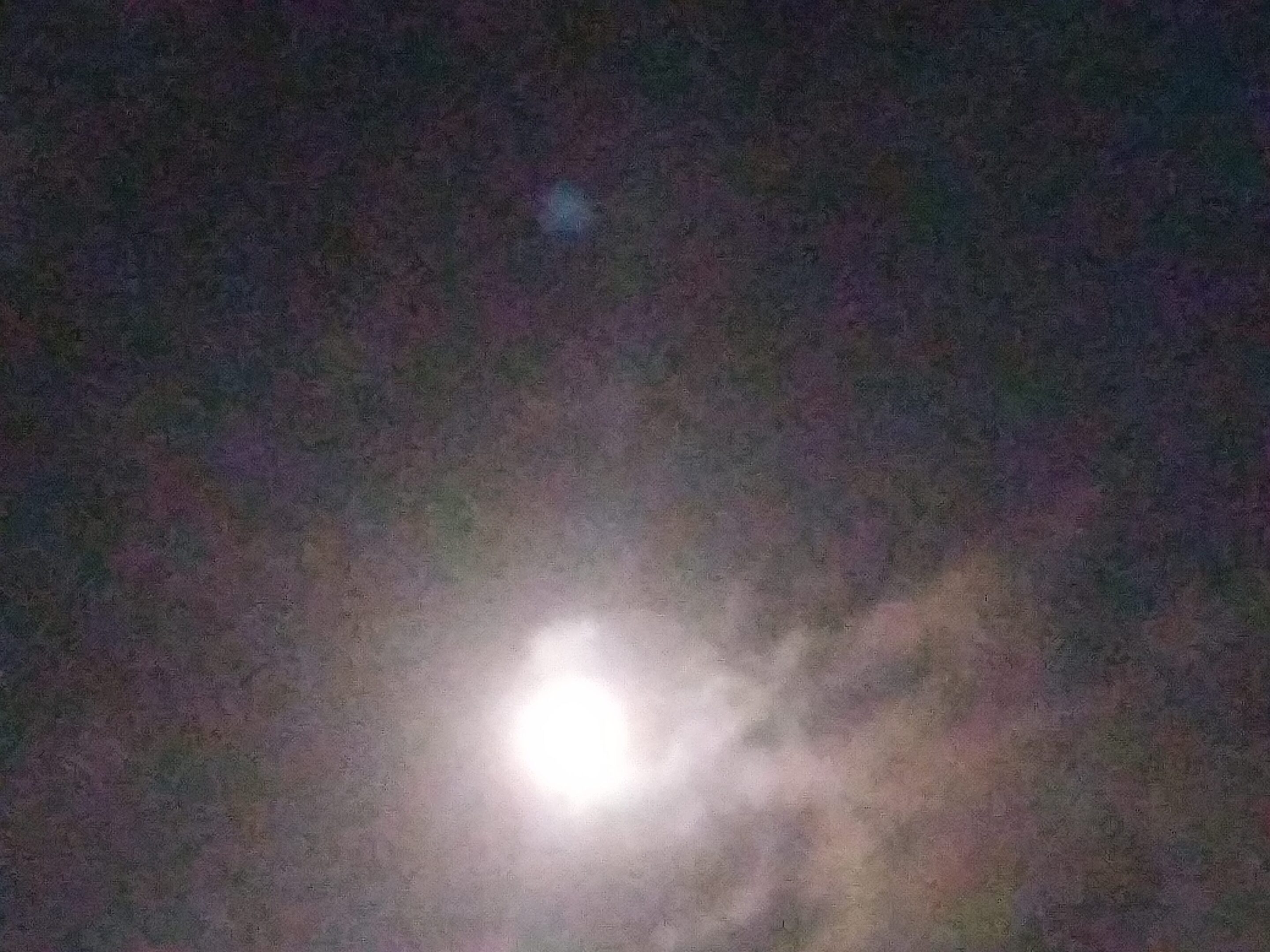 Bright moon in a cloudy night sky.