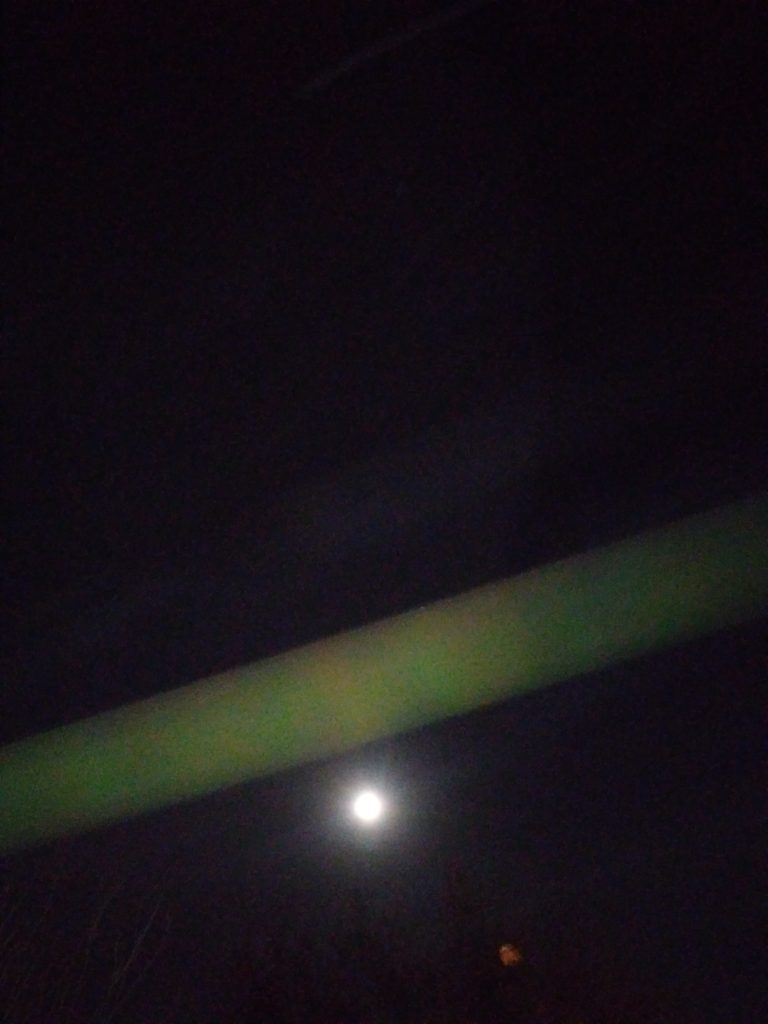 Night sky with moon and green light.