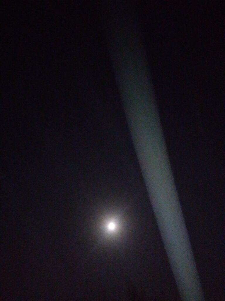 Moon shining in dark night sky, light beam.