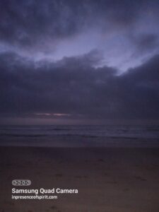 Dark beach scene with cloudy sky.