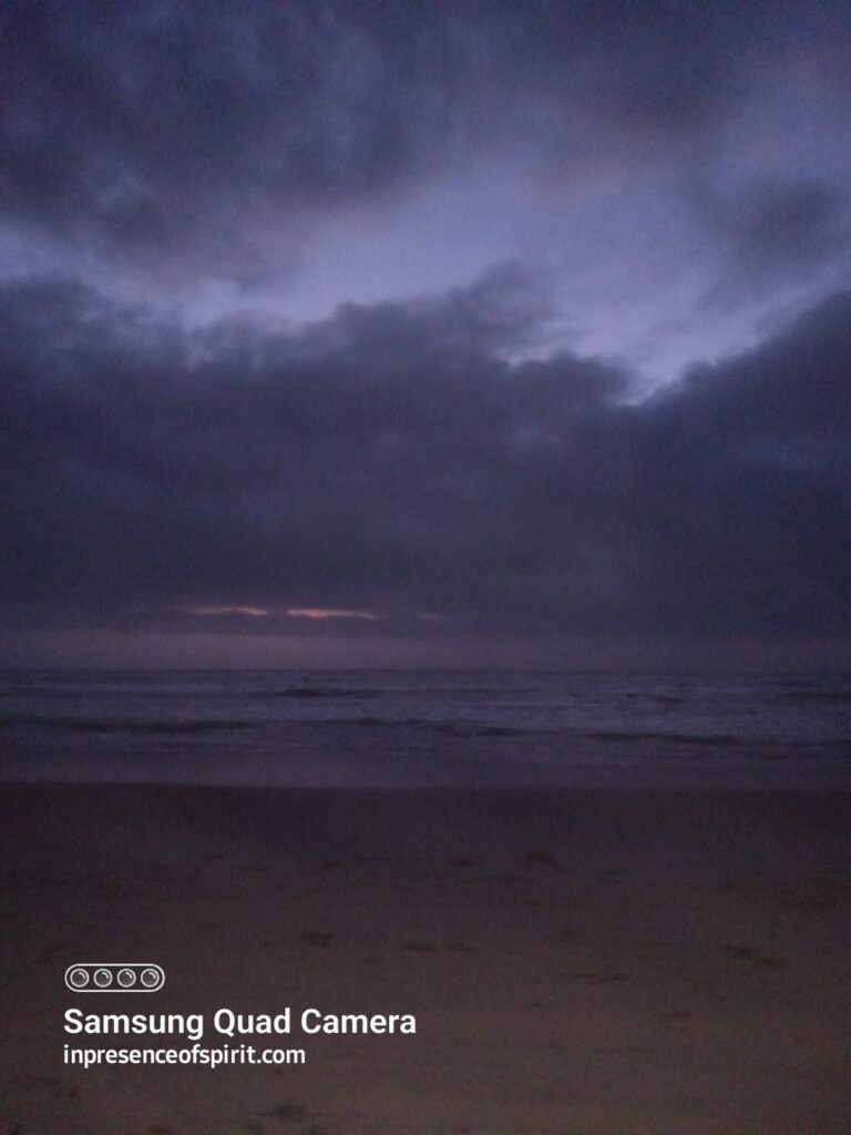 Dark beach scene with cloudy sky.