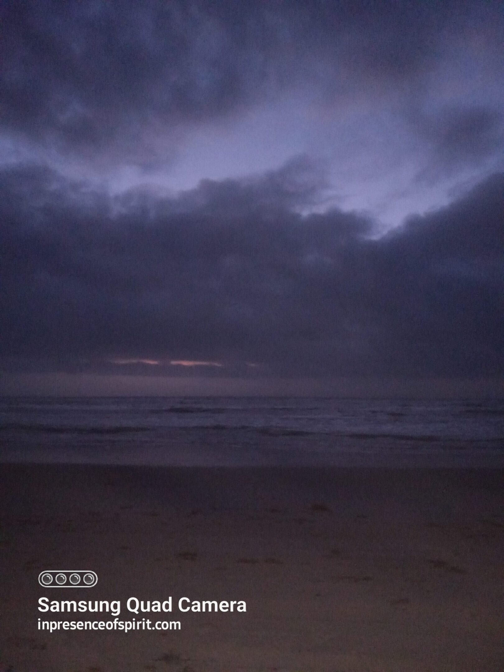 Dark beach scene with cloudy sky.