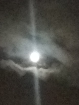 Bright moon surrounded by clouds at night.