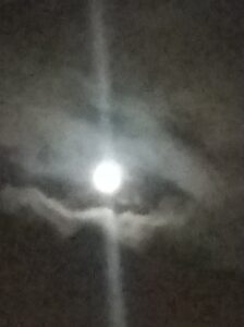 Bright moon surrounded by clouds at night.