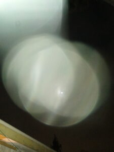 Blurry light orb in dark sky.