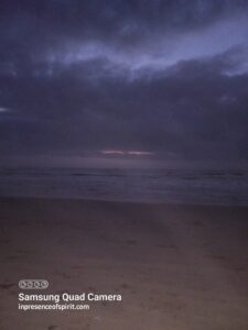 Dark beach at twilight with cloudy sky.