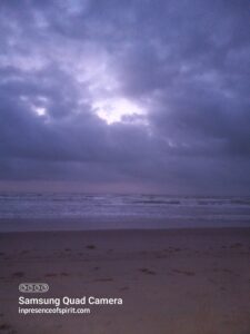 Cloudy beach at twilight with dark sky.