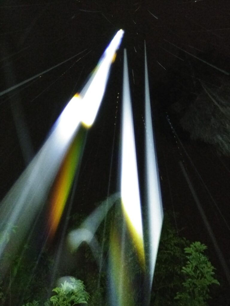 Colorful light beams against dark night sky.