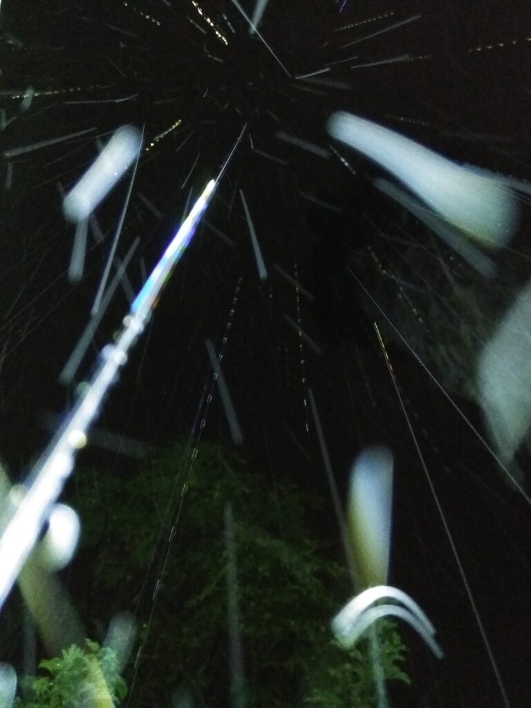 Nighttime rain with bright light streaks.