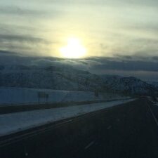 Sunset over snowy mountain and road.