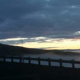 Sunset over hills and foggy landscape.