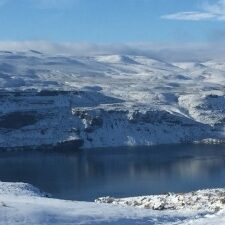 Snowy mountains and lake under blue sky.