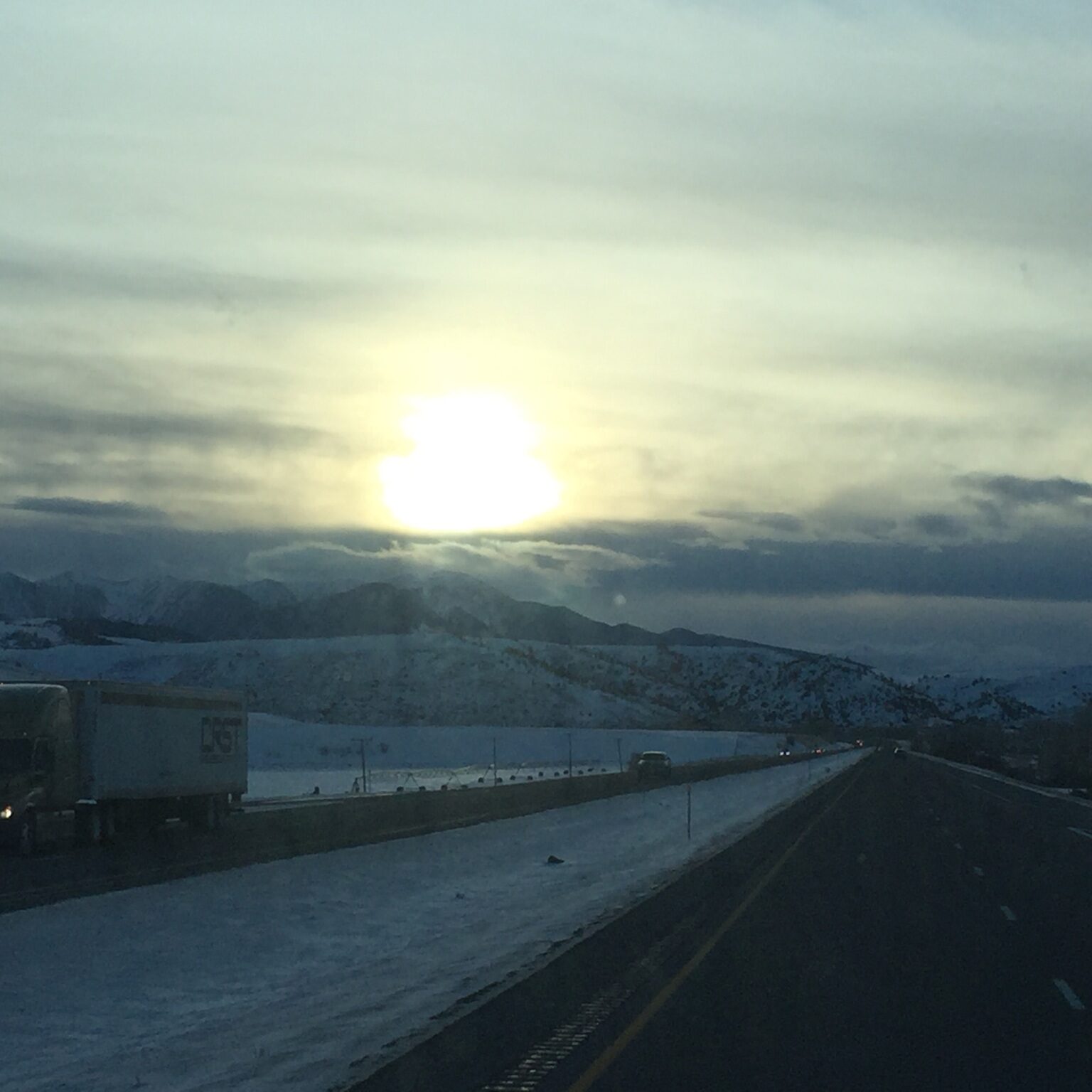 Sunset over snowy highway with truck.