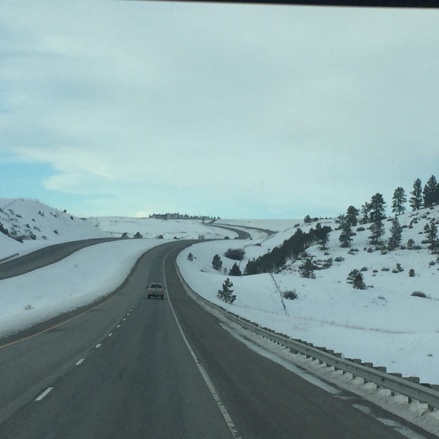 Snowy highway winding through hilly landscape.