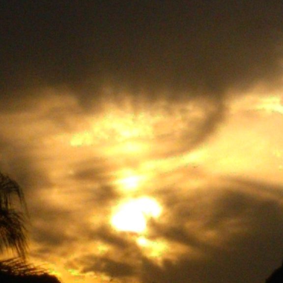 Dramatic sunset with silhouetted trees and clouds.
