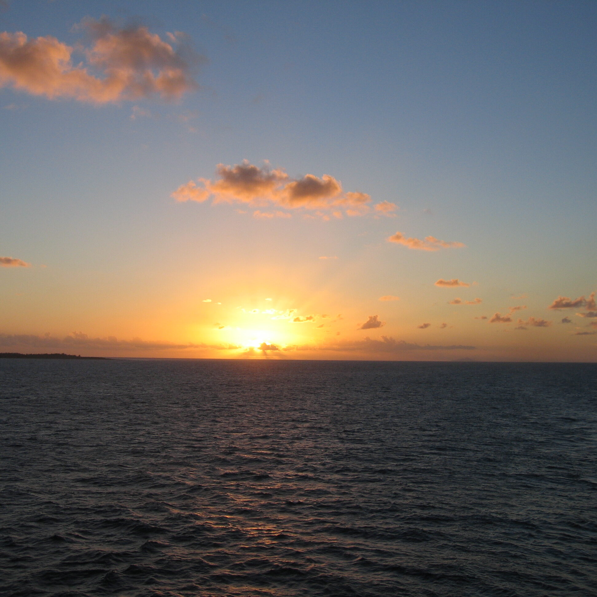 Ocean sunset with scattered clouds.