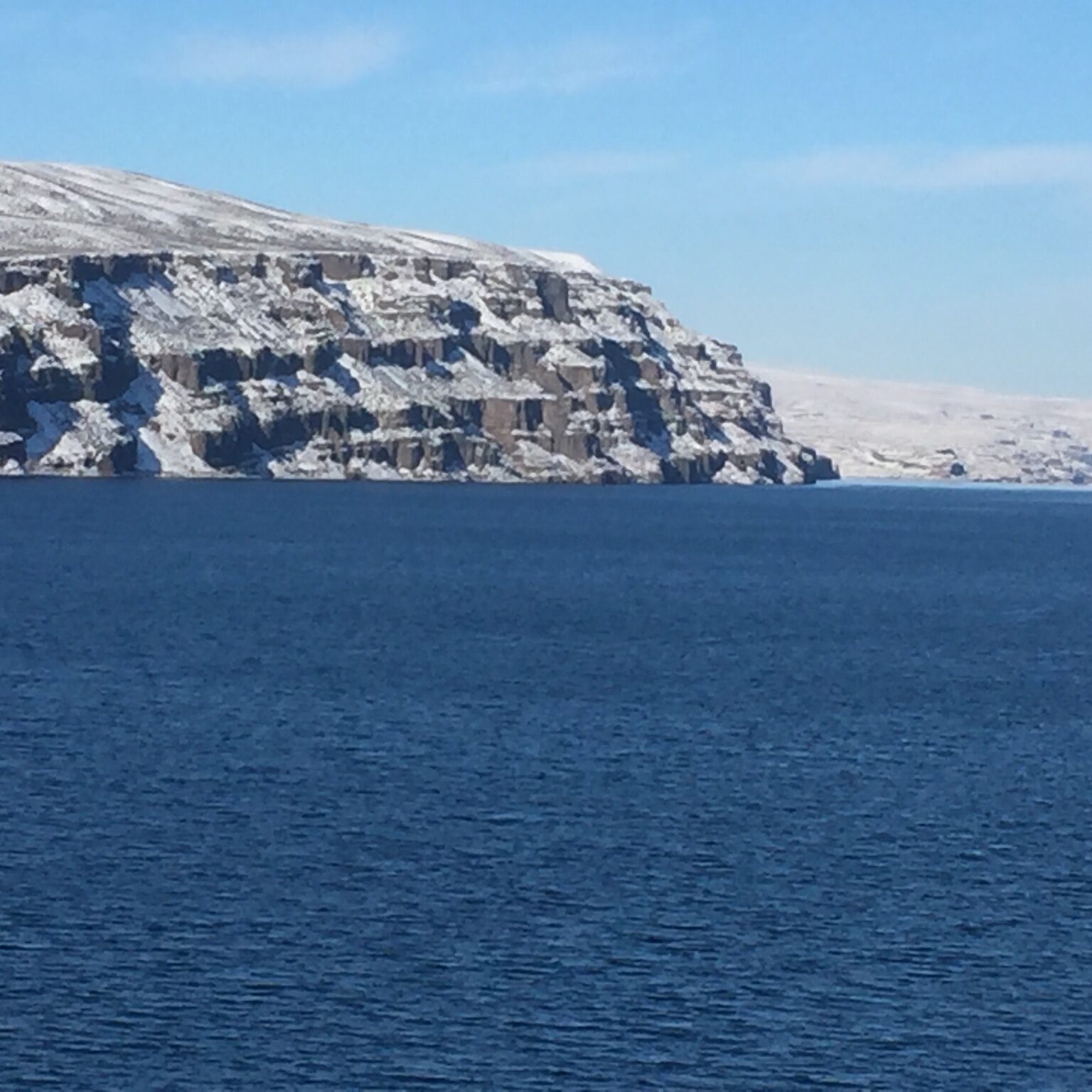 Snowy cliffs beside a calm blue sea.