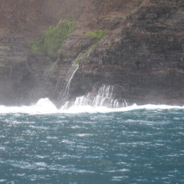 Waterfall cascading down rocky cliffside into ocean.