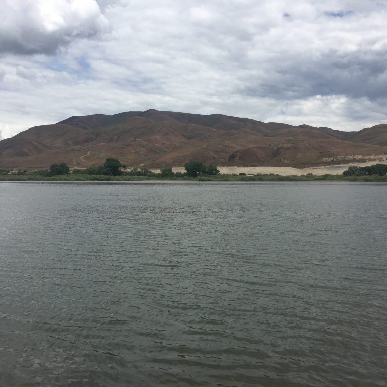 River with hills under a cloudy sky.