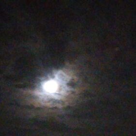 Bright moon glowing through the cloudy night.