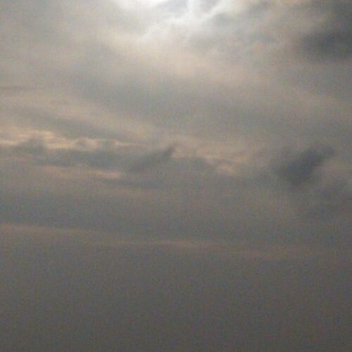 Cloudy sky over water with sunlight reflection.