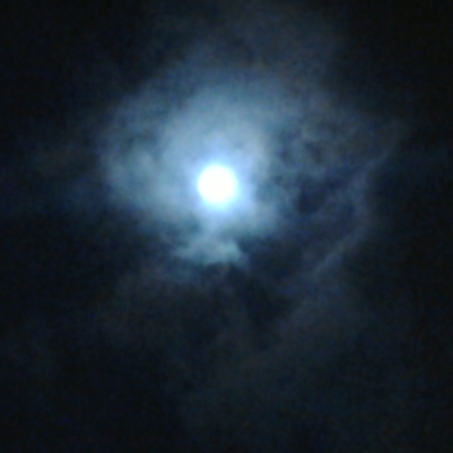 Bright moon surrounded by dark, cloudy sky.