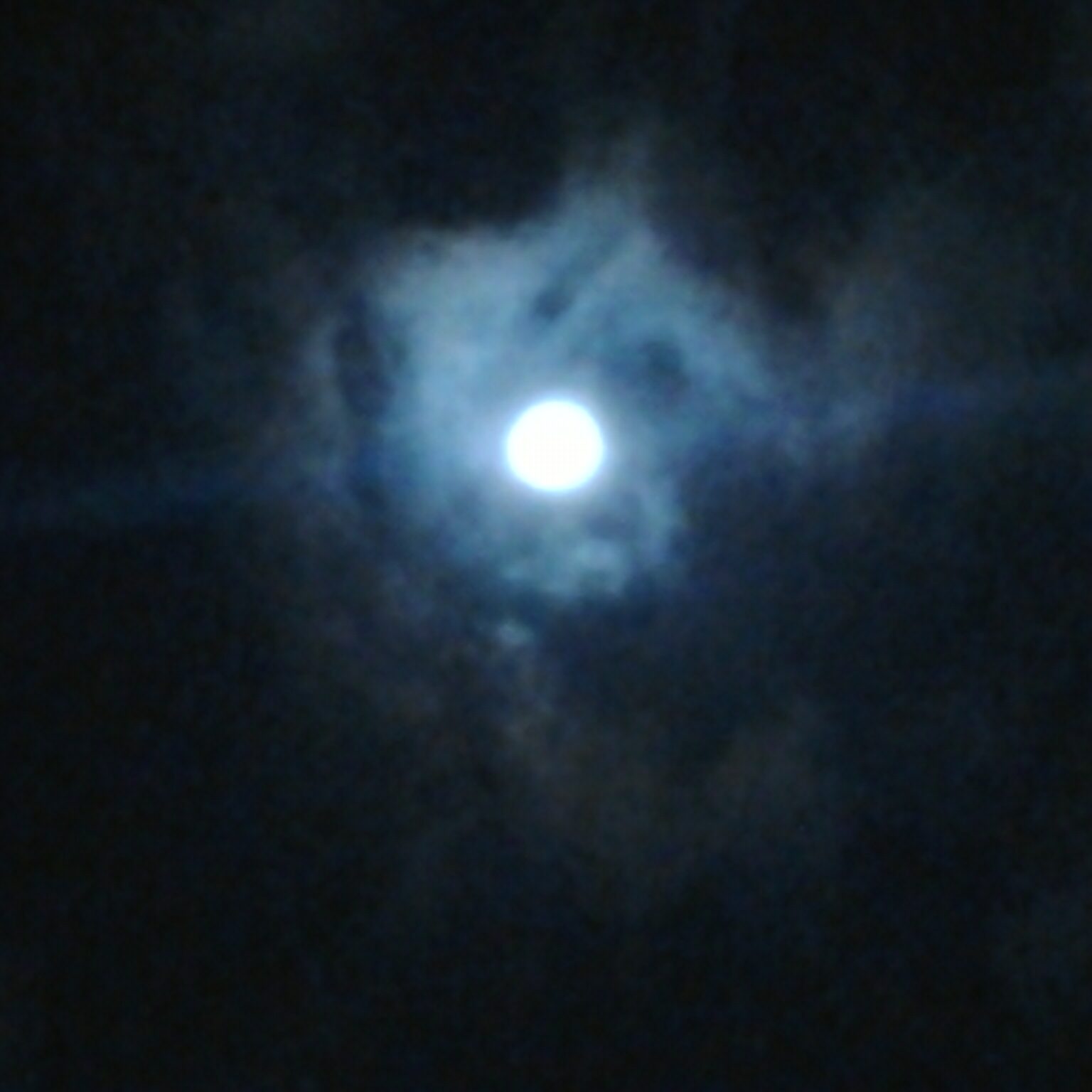 Moon shining through dark, cloudy night sky.